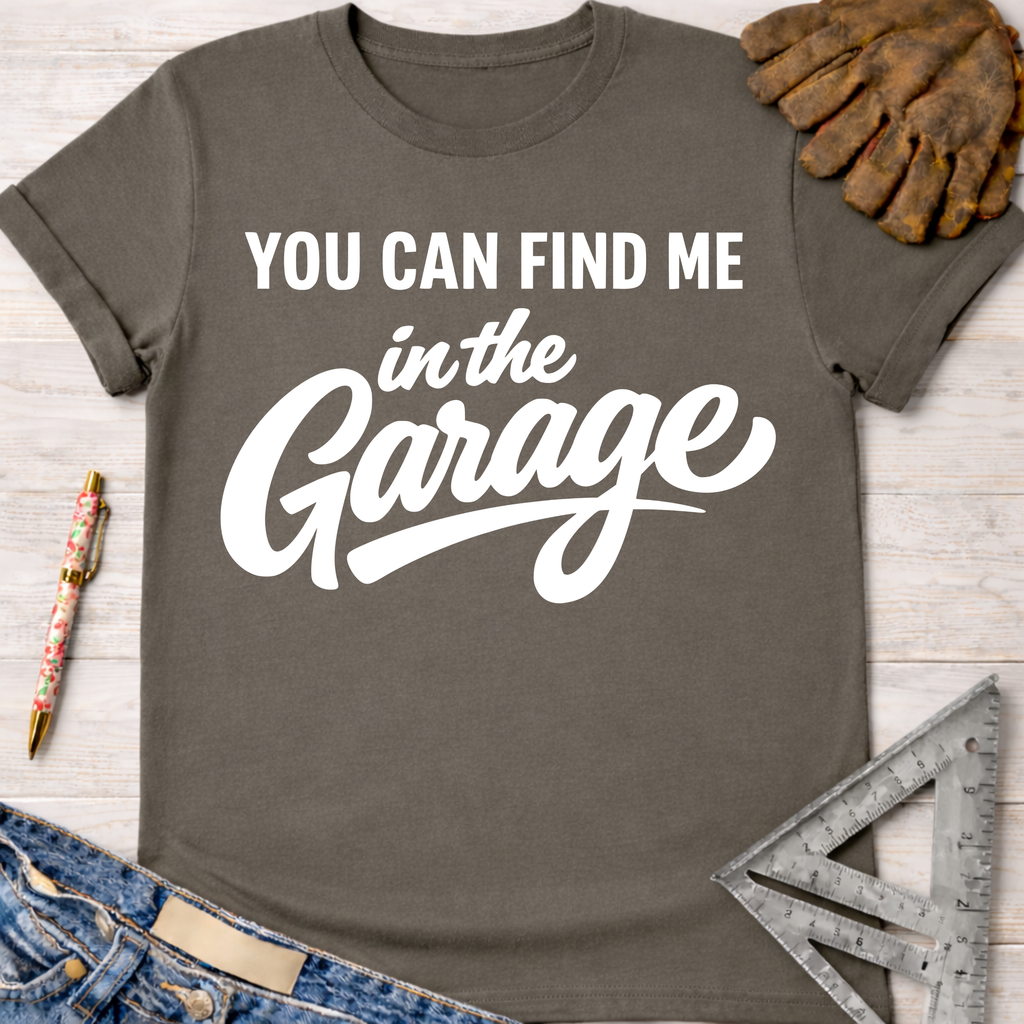 Women's funny woodworking graphic tee shirt for female woodworkers, makers, and DIY builders — Sawdust & Ponytails. Charcoal gray cotton tee with "YOU CAN FIND ME in the Garage" in white script.