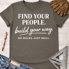 Women's funny woodworking graphic tee shirt for female woodworkers, makers, and DIY builders — Sawdust & Ponytails. Dark gray t-shirt with "FIND YOUR PEOPLE. build your way. NO RULES. JUST SKILL." in white text, styled with jeans, pen, glove, and ruler.