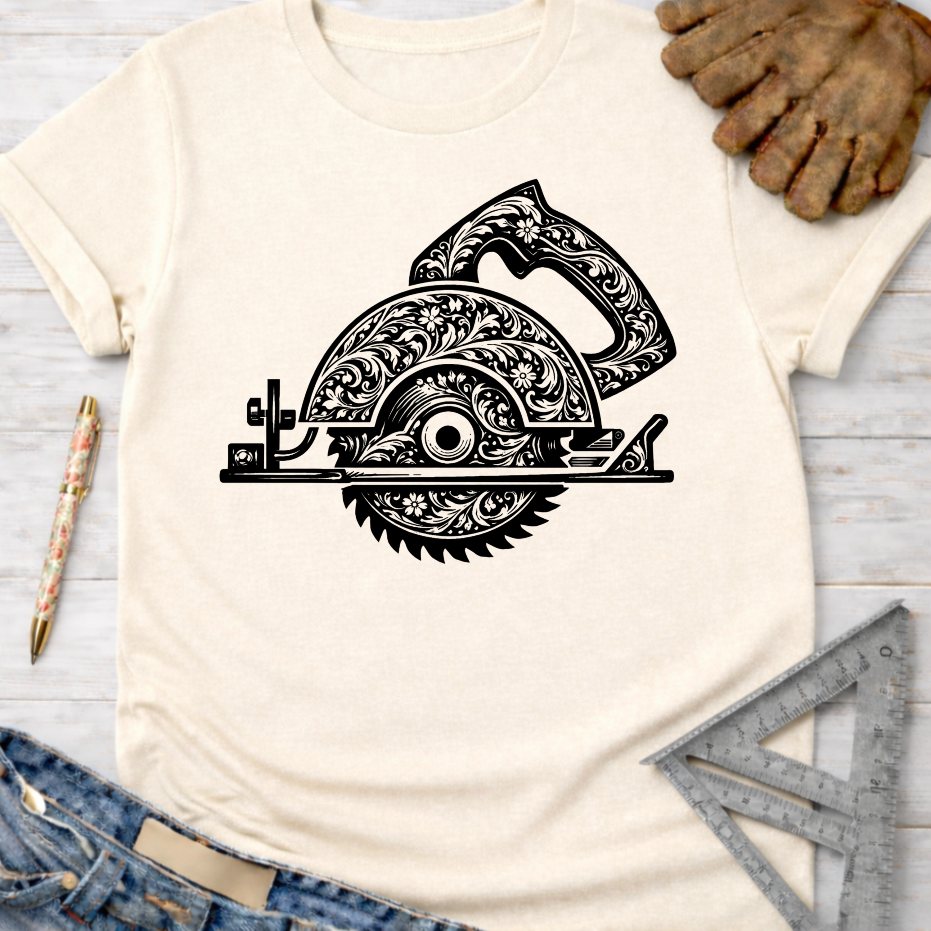 Women's funny woodworking graphic tee shirt for female woodworkers, makers, and DIY builders — Sawdust & Ponytails. Cream t-shirt with a black floral engraved circular saw design.