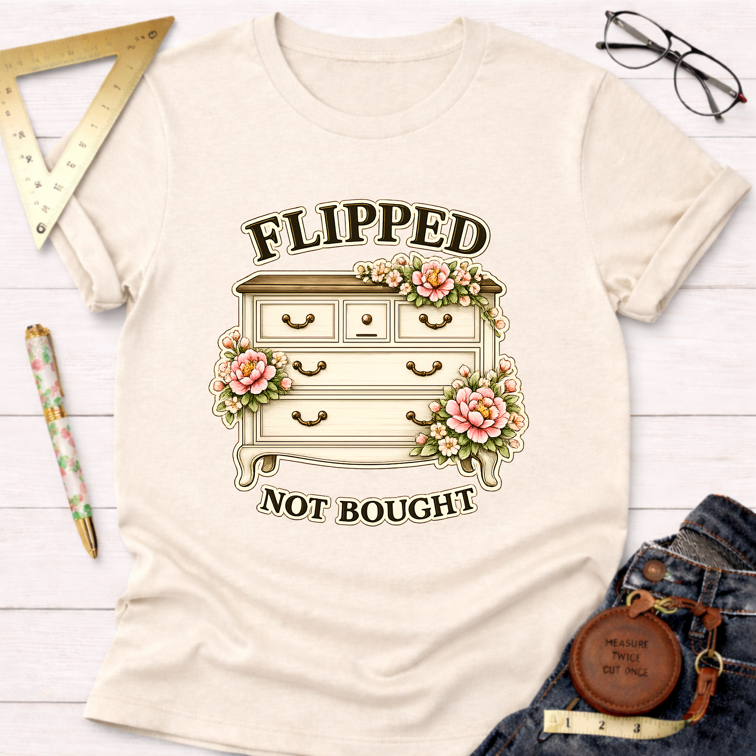 Cream t-shirt with "Flipped Not Bought" text and a floral decorated dresser graphic.
