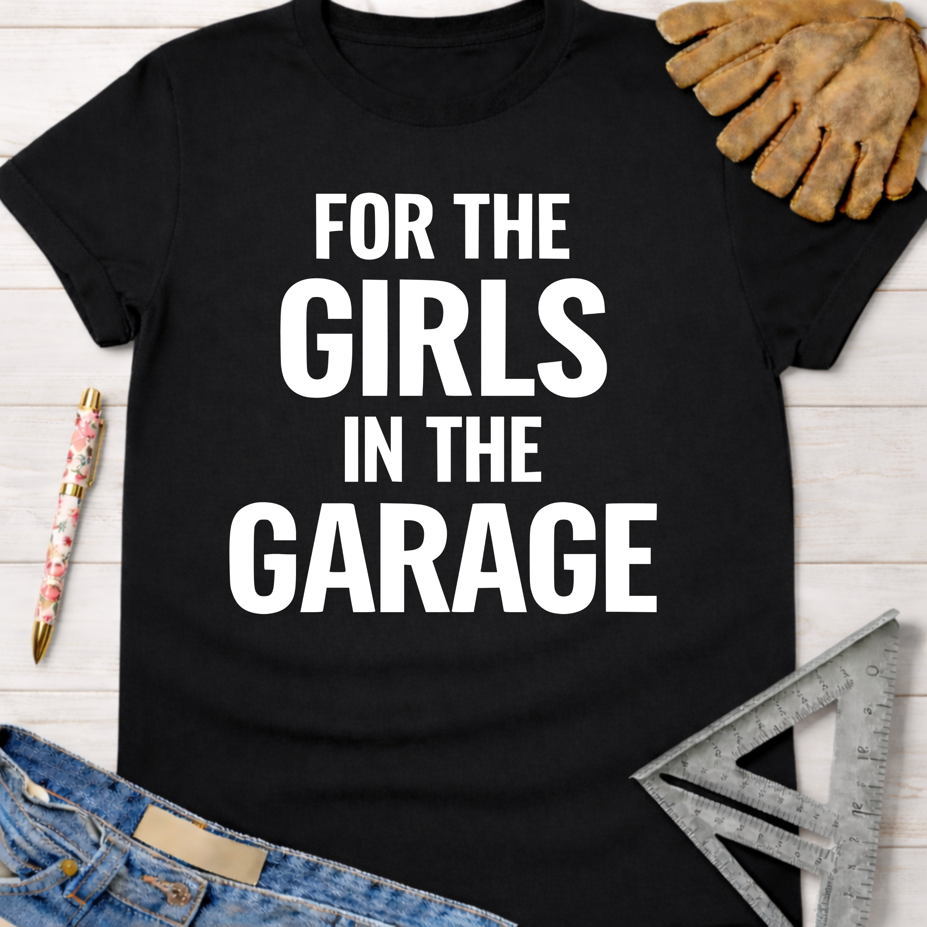 Black cotton "FOR THE GIRLS IN THE GARAGE" graphic tee, with work gloves, jeans, and a ruler.