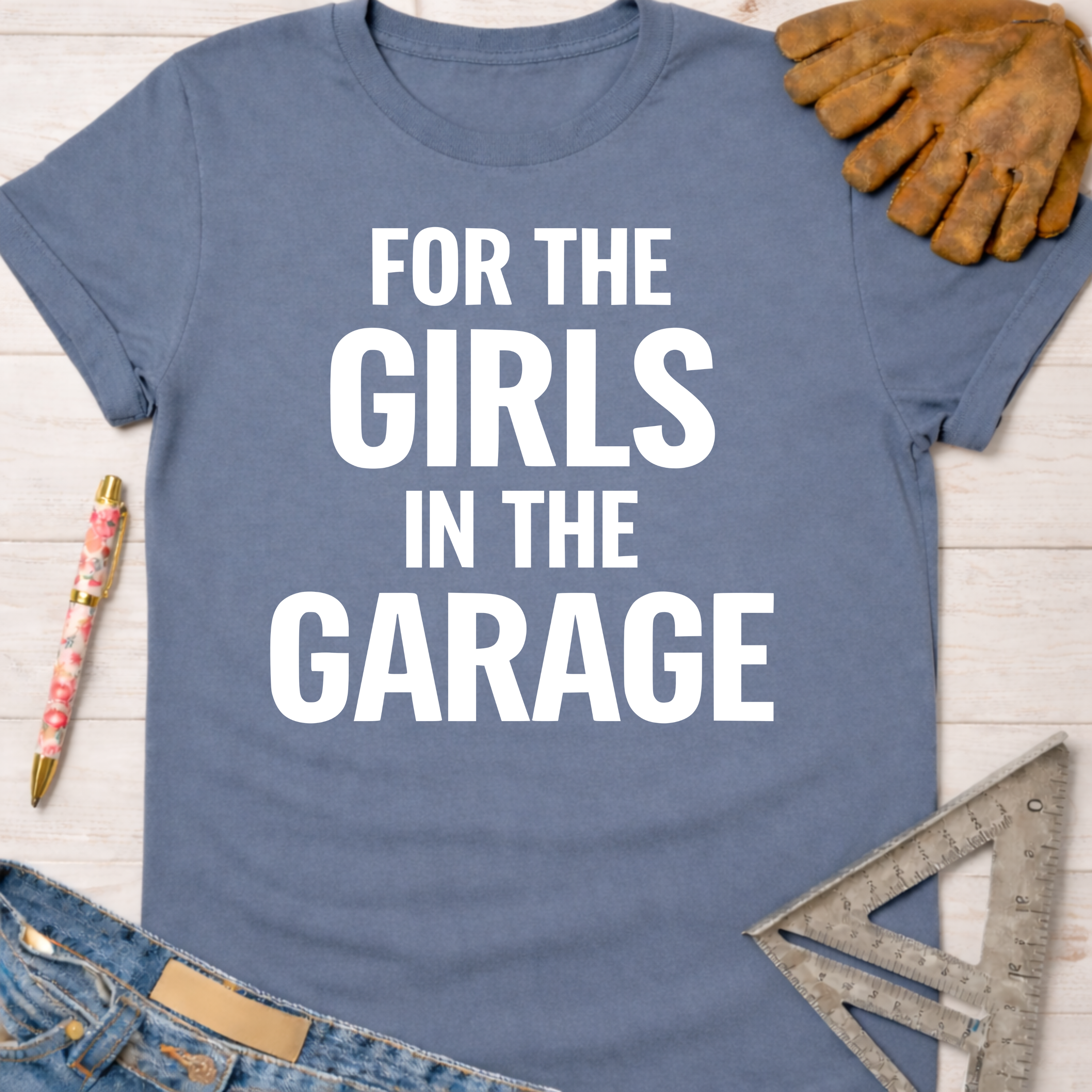 Women's funny woodworking graphic tee shirt for female woodworkers, makers, and DIY builders — Sawdust & Ponytails. Blue cotton t-shirt with "FOR THE GIRLS IN THE GARAGE" in white text.