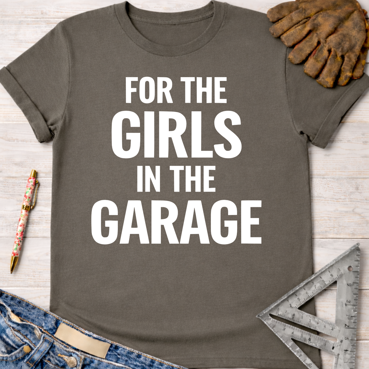 Women's funny woodworking graphic tee shirt for female woodworkers, makers, and DIY builders — Sawdust & Ponytails. Dark gray cotton tee with "FOR THE GIRLS IN THE GARAGE" in white text.