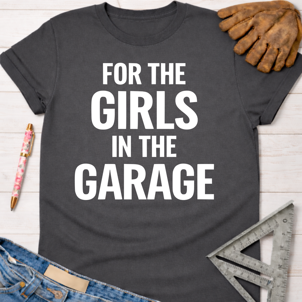 Women's funny woodworking graphic tee shirt for female woodworkers, makers, and DIY builders — Sawdust & Ponytails. Dark gray cotton tee with "FOR THE GIRLS IN THE GARAGE" in white text.