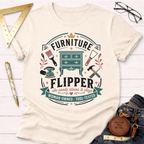 Cream "Furniture Flipper" t-shirt with a teal, brown, and pink graphic of tools and a dresser.