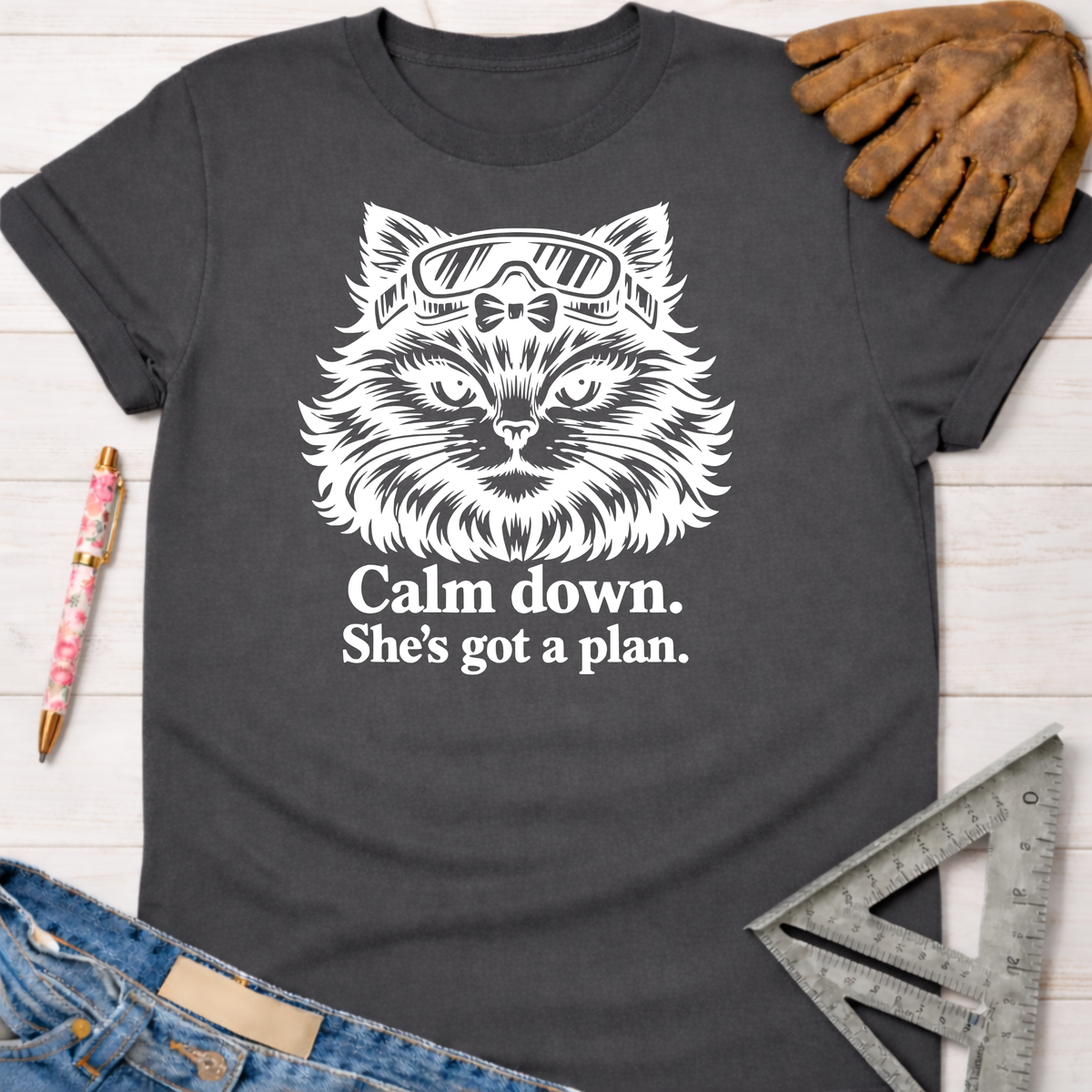 Charcoal gray Gato With A Plan T-Shirt with white cat graphic wearing goggles, "Calm down. She's got a plan." text. Women's funny woodworking graphic tee shirt for female woodworkers, makers, and DIY builders — Sawdust & Ponytails