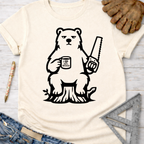 Women's funny woodworking graphic tee shirt for female woodworkers, makers, and DIY builders — Sawdust & Ponytails. Cream short-sleeve tee with a black graphic of a grumpy bear holding a saw and "I Love Wood" mug, sitting on a tree stump.