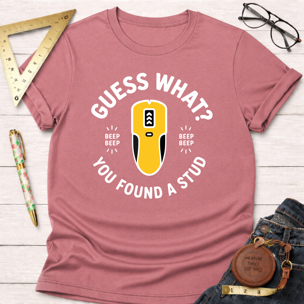 Pink crewneck t-shirt with "Guess What? You Found A Stud" text and a yellow stud finder graphic.