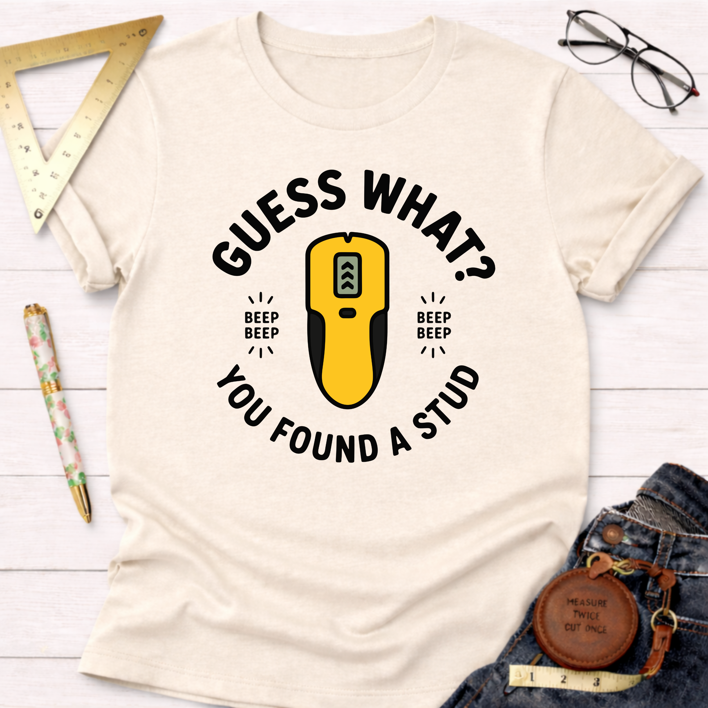 Cream t-shirt with "Guess What? You Found A Stud" text and a yellow stud finder graphic.
