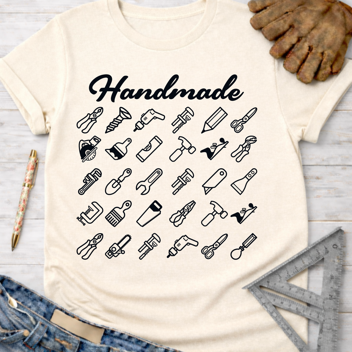 Women's funny woodworking graphic tee shirt for female woodworkers, makers, and DIY builders — Sawdust & Ponytails. Cream tee with "Handmade" and black tool icons.