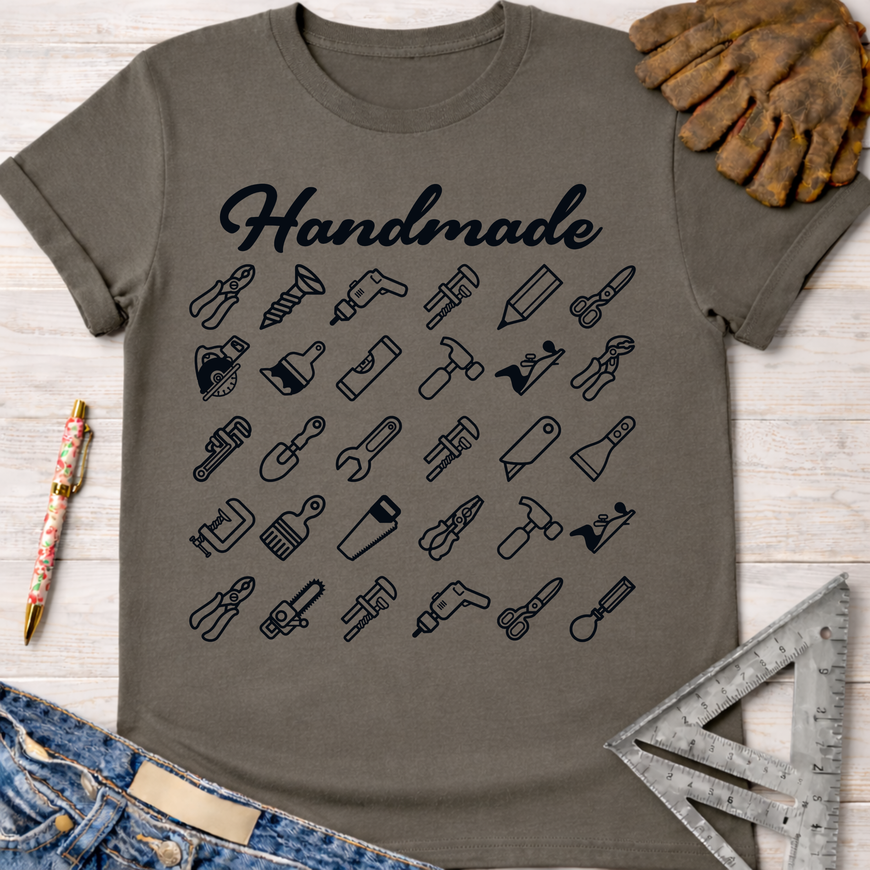 Women's funny woodworking graphic tee shirt for female woodworkers, makers, and DIY builders — Sawdust & Ponytails. Dark gray cotton tee with "Handmade" text and tool icons.