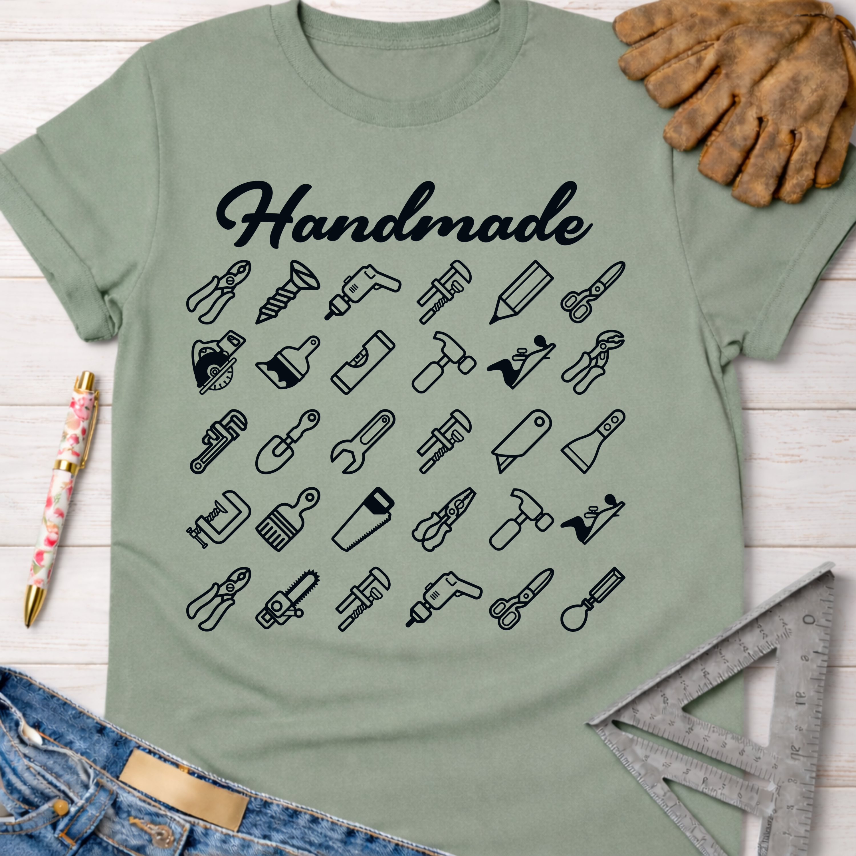 Women's funny woodworking graphic tee shirt for female woodworkers, makers, and DIY builders — Sawdust & Ponytails. Light green tee with "Handmade" script and tool icons.