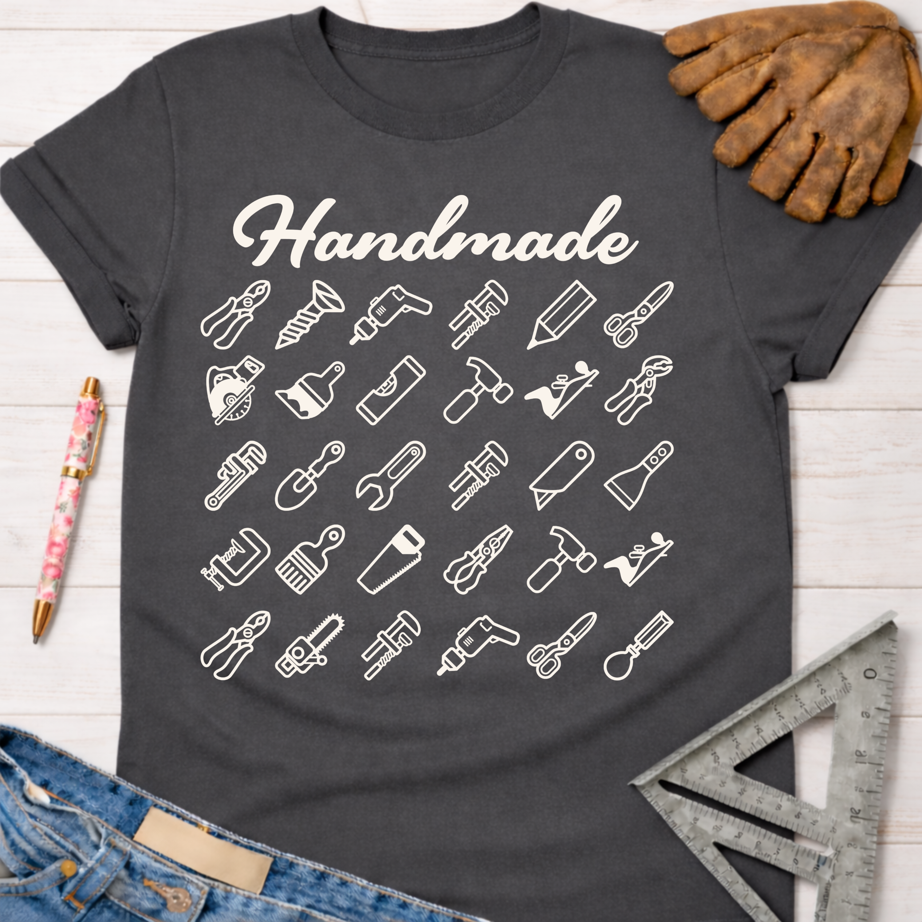 Women's funny woodworking graphic tee shirt for female woodworkers, makers, and DIY builders — Sawdust & Ponytails. Dark gray tee with "Handmade" and white tool icons.
