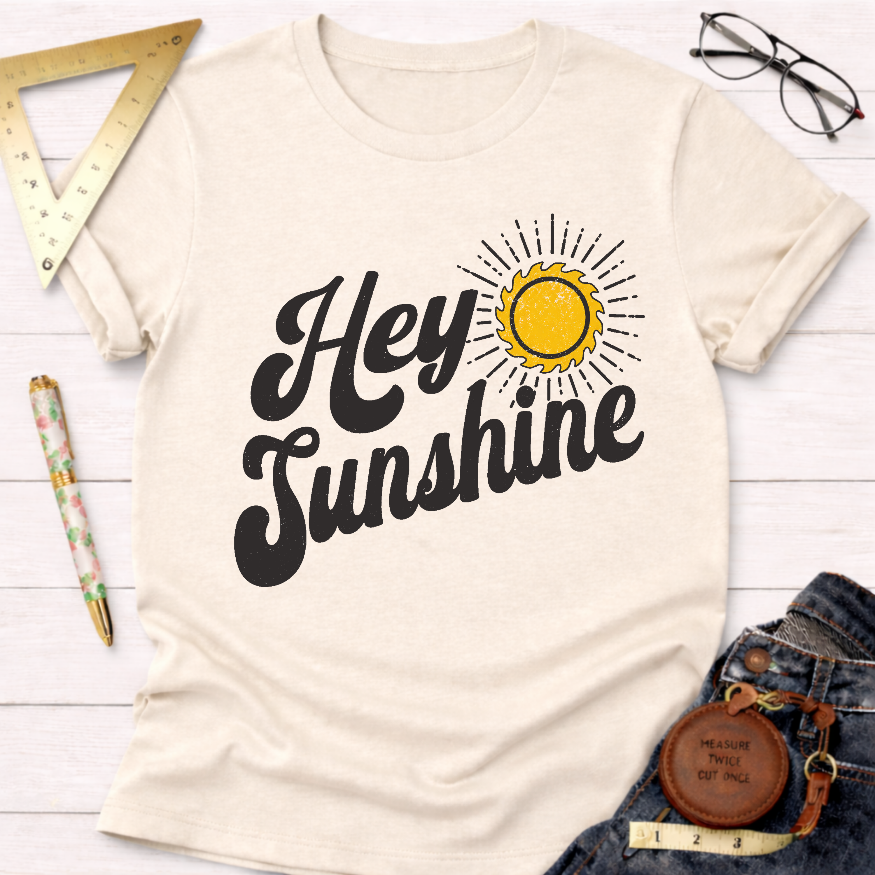 Women's funny woodworking graphic tee shirt for female woodworkers, makers, and DIY builders — Sawdust & Ponytails. Cream t-shirt with "Hey Sunshine" text and a yellow sun graphic.