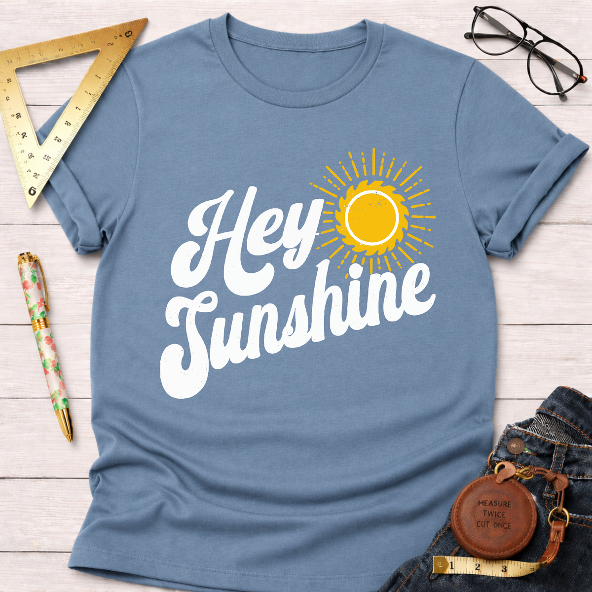 Women's funny woodworking graphic tee shirt for female woodworkers, makers, and DIY builders — Sawdust & Ponytails. Blue cotton t-shirt with "Hey Sunshine" text and a yellow sun graphic.