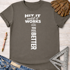 Women's funny woodworking graphic tee shirt for female woodworkers, makers, and DIY builders — Sawdust & Ponytails. Dark gray t-shirt with "HIT IT until it works OR UNTIL YOU FEEL BETTER" in white text, forming a hammer shape.