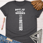 Women's funny woodworking graphic tee shirt for female woodworkers, makers, and DIY builders — Sawdust & Ponytails. Dark gray cotton t-shirt with "HIT IT until it works OR UNTIL YOU FEEL BETTER" in white text.