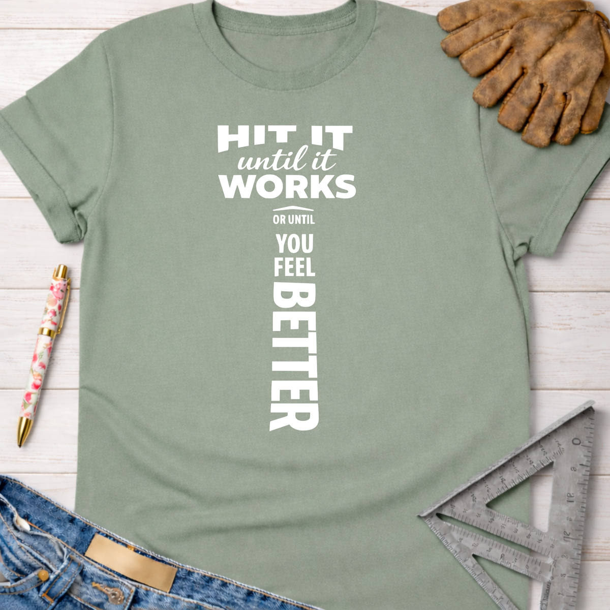 Women's funny woodworking graphic tee shirt for female woodworkers, makers, and DIY builders — Sawdust & Ponytails. Sage green cotton t-shirt with "HIT IT until it works OR UNTIL YOU FEEL BETTER" in white text.