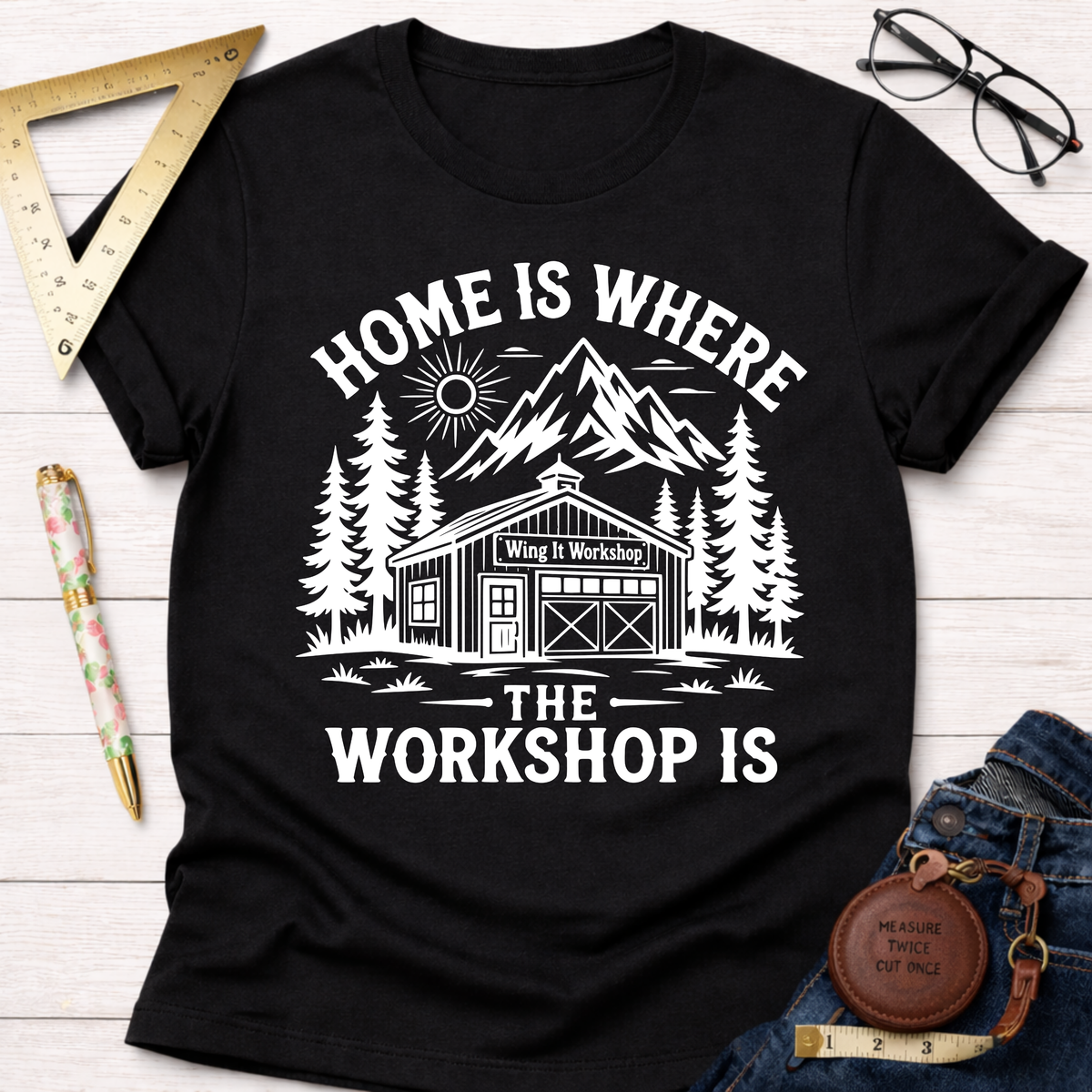 Black cotton women's funny woodworking graphic tee with "Home Is Where The Workshop Is" design. Sawdust & Ponytails.