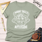 Sage green cotton t-shirt with a white graphic of a horned bull wearing goggles, holding tools, and text "Horns, Skills, & A Bad Attitude.