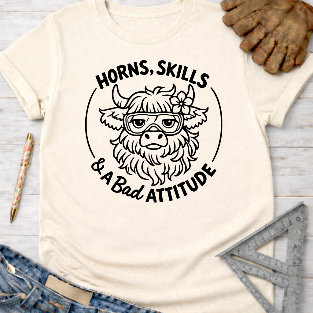 Women's funny woodworking graphic tee shirt for female woodworkers, makers, and DIY builders — Sawdust & Ponytails. Cream t-shirt with "Horns, Skills & A Bad Attitude" highland cow graphic.