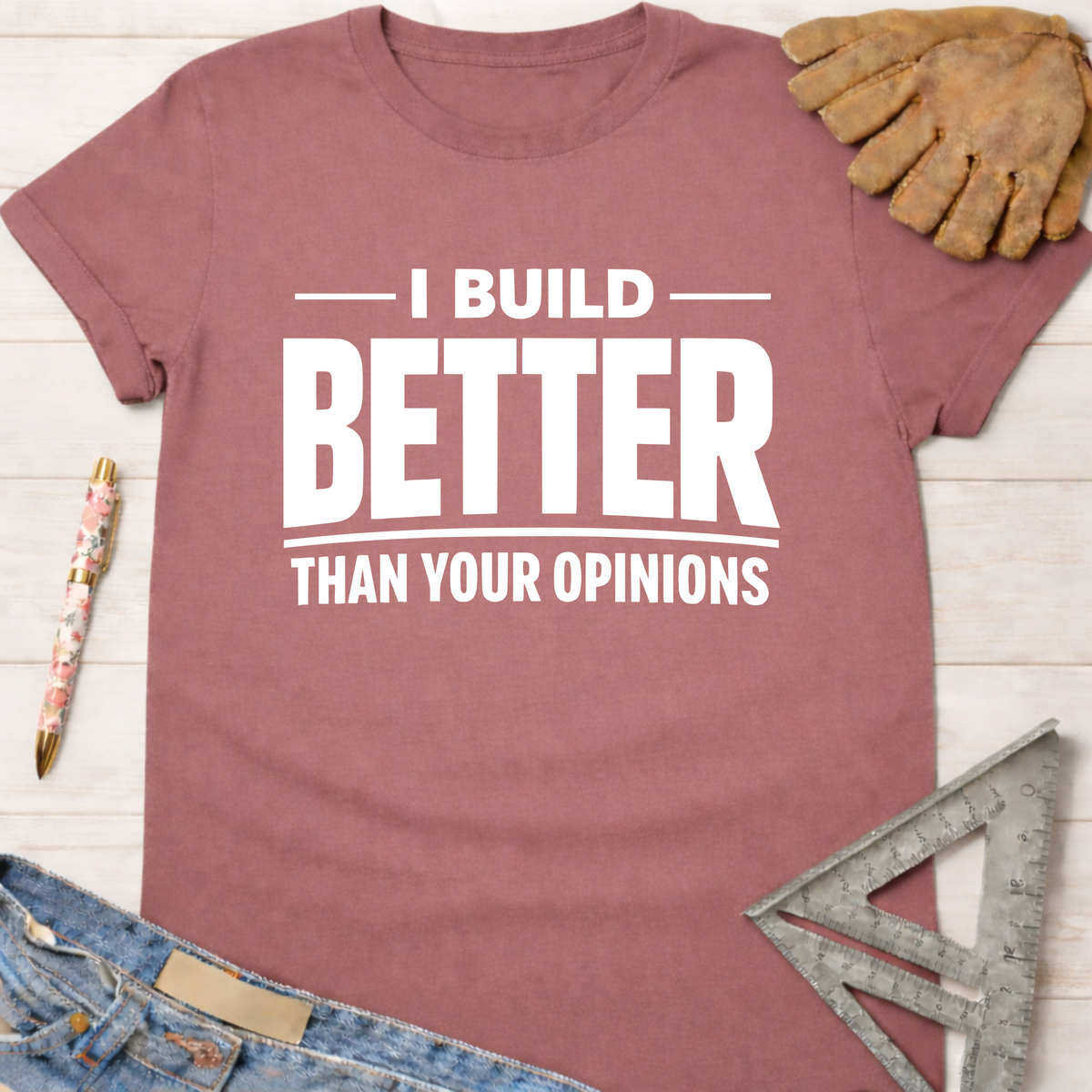 Women's funny woodworking graphic tee shirt for female woodworkers, makers, and DIY builders — Sawdust & Ponytails. Mauve cotton t-shirt with "I BUILD BETTER THAN YOUR OPINIONS" in white text.
