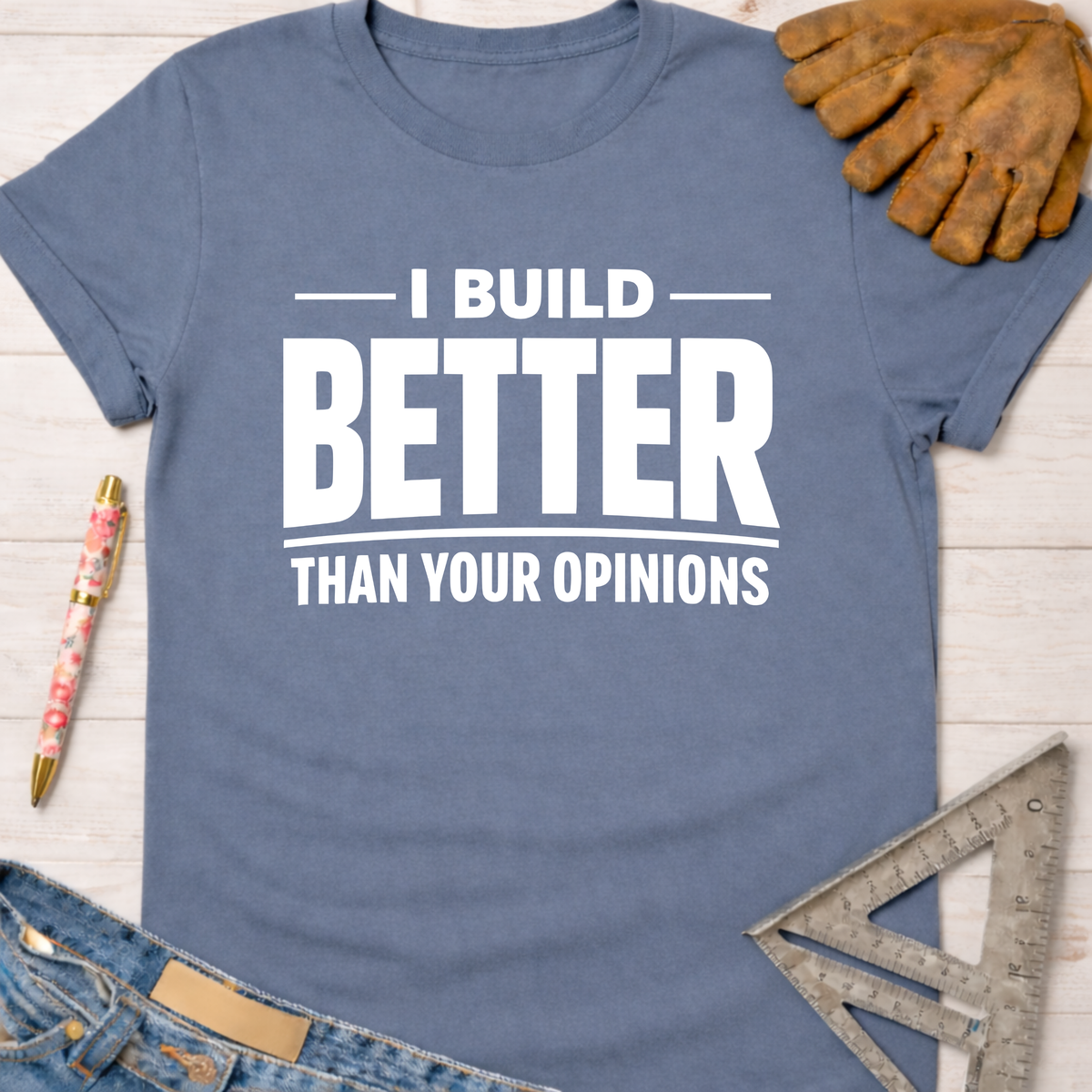 Women's funny woodworking graphic tee shirt for female woodworkers, makers, and DIY builders — Sawdust & Ponytails. Blue short-sleeve tee with "I BUILD BETTER THAN YOUR OPINIONS" in white text.