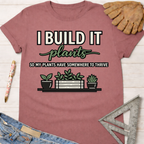Women's funny woodworking graphic tee shirt for female woodworkers, makers, and DIY builders — Sawdust & Ponytails. Mauve cotton tee with "I BUILD IT plants SO MY PLANTS HAVE SOMEWHERE TO THRIVE" graphic.