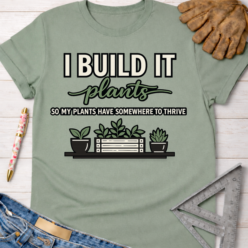 Women's funny woodworking graphic tee shirt for female woodworkers, makers, and DIY builders — Sawdust & Ponytails. Sage green cotton tee with "I Build It So My Plants Have Somewhere To Thrive" graphic.