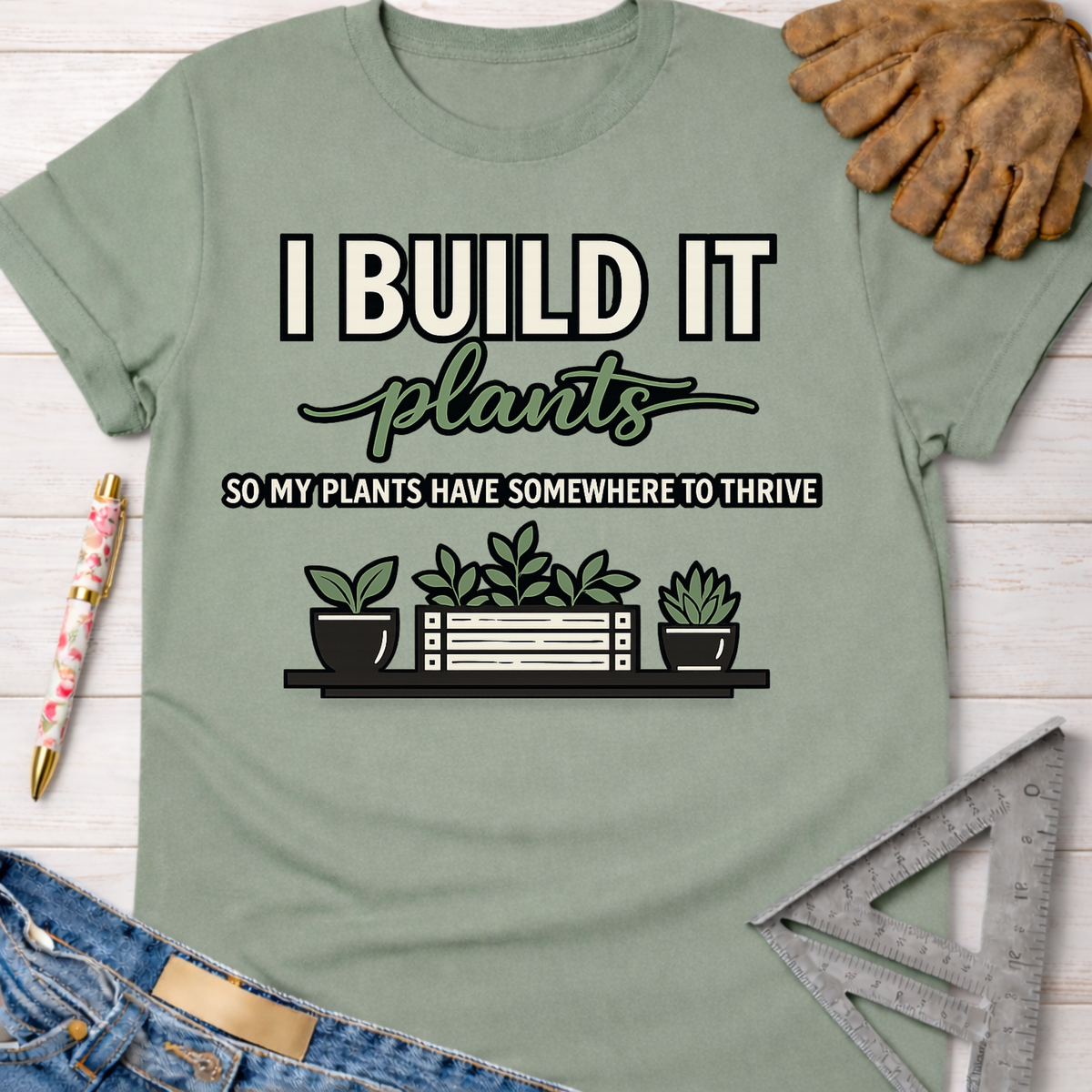 Women's funny woodworking graphic tee shirt for female woodworkers, makers, and DIY builders — Sawdust & Ponytails. Sage green cotton tee with "I Build It So My Plants Have Somewhere To Thrive" graphic.