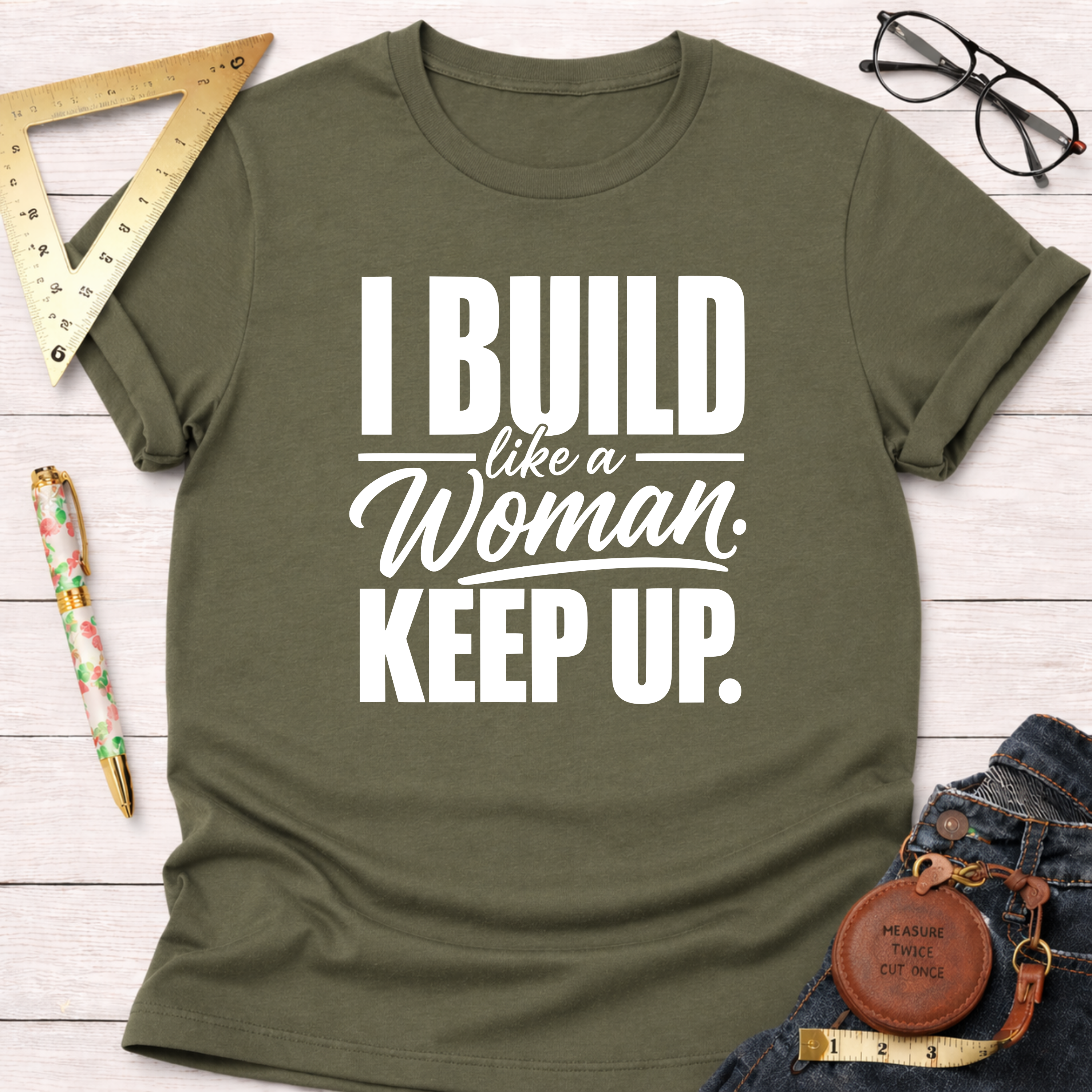 Olive green cotton t-shirt with "I Build Like A Woman. Keep Up." in white text, styled with tools.
