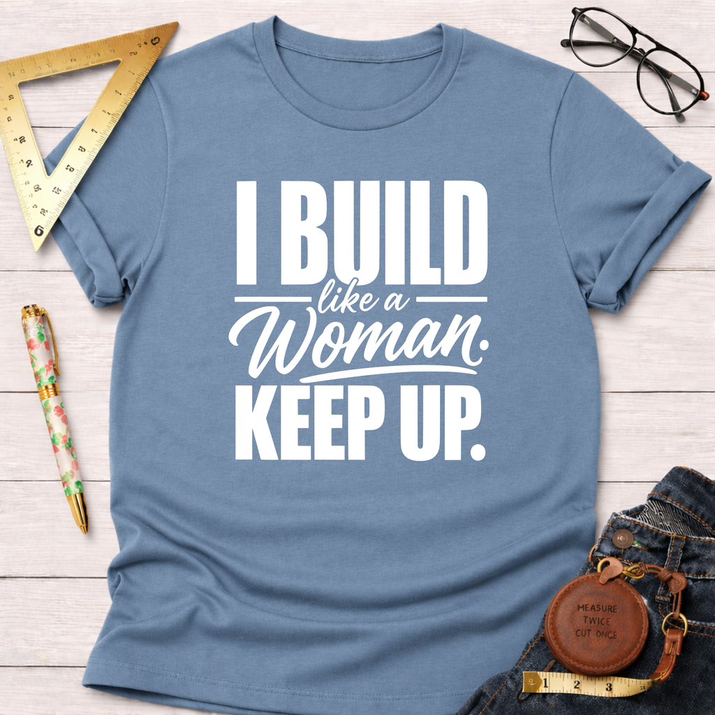 Blue cotton t-shirt with "I Build Like A Woman. Keep Up." in white text, styled with jeans and tools.