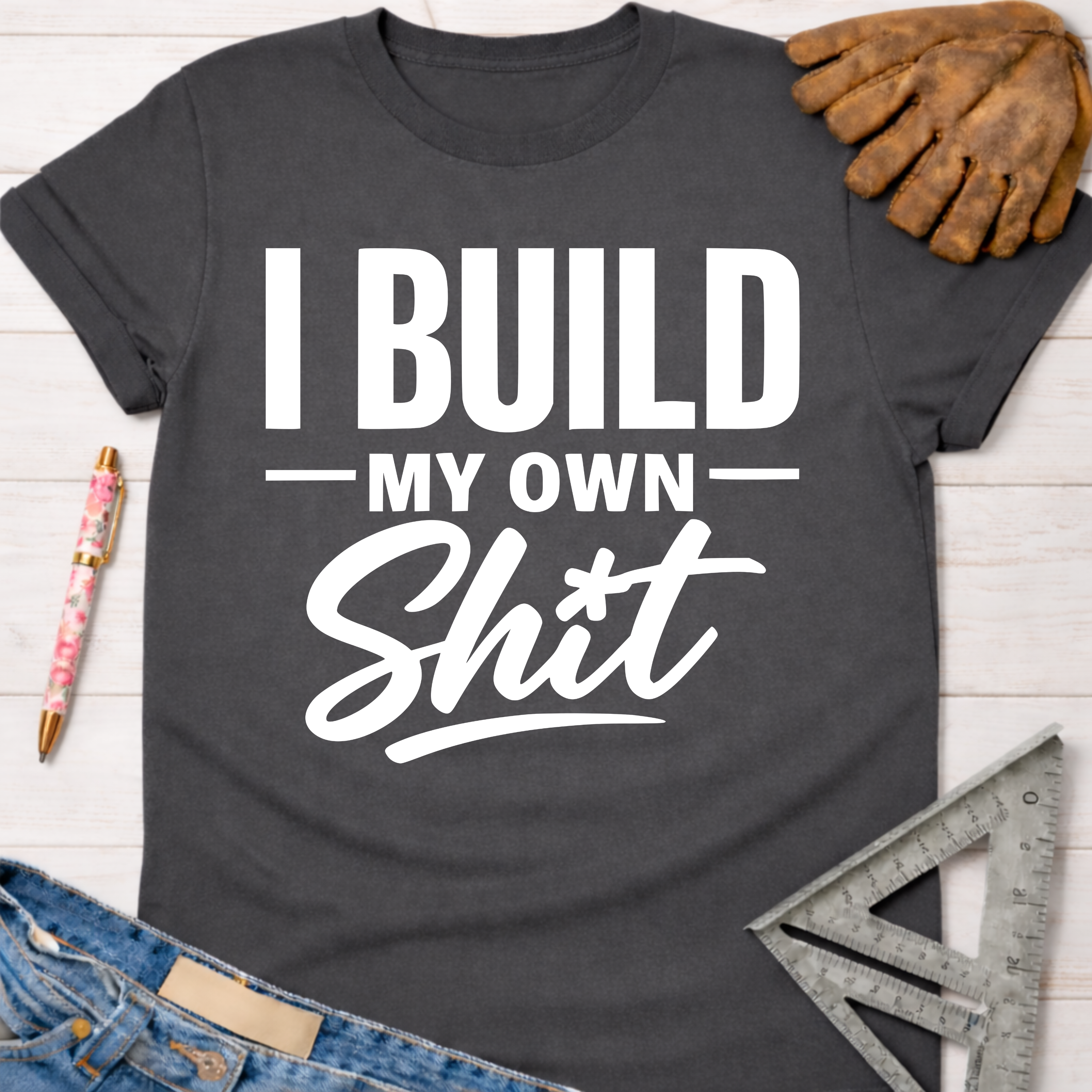 Women's funny woodworking graphic tee shirt for female woodworkers, makers, and DIY builders — Sawdust & Ponytails. Dark gray cotton tee with "I Build My Own Shit" in white text.