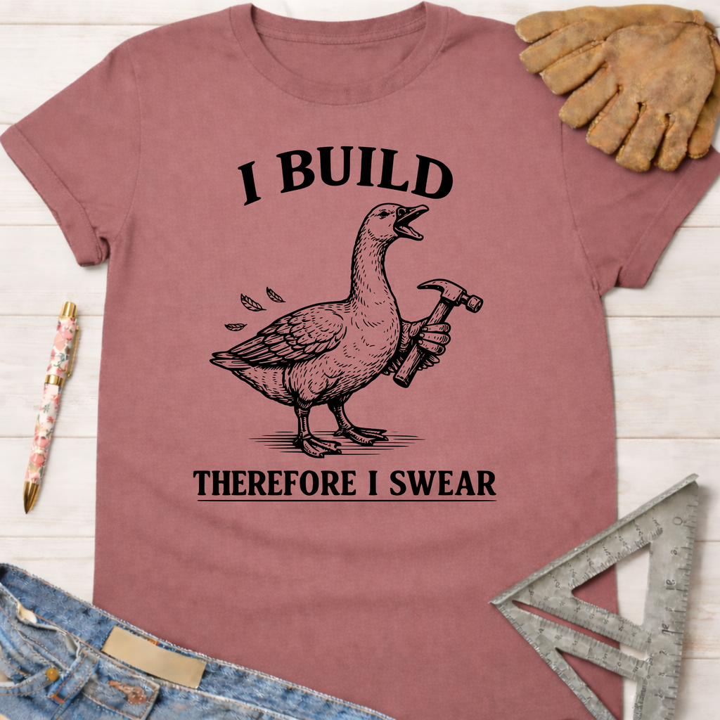 Women's funny woodworking graphic tee shirt for female woodworkers, makers, and DIY builders — Sawdust & Ponytails. Mauve cotton tee with a goose holding a hammer and "I Build Therefore I Swear" text.