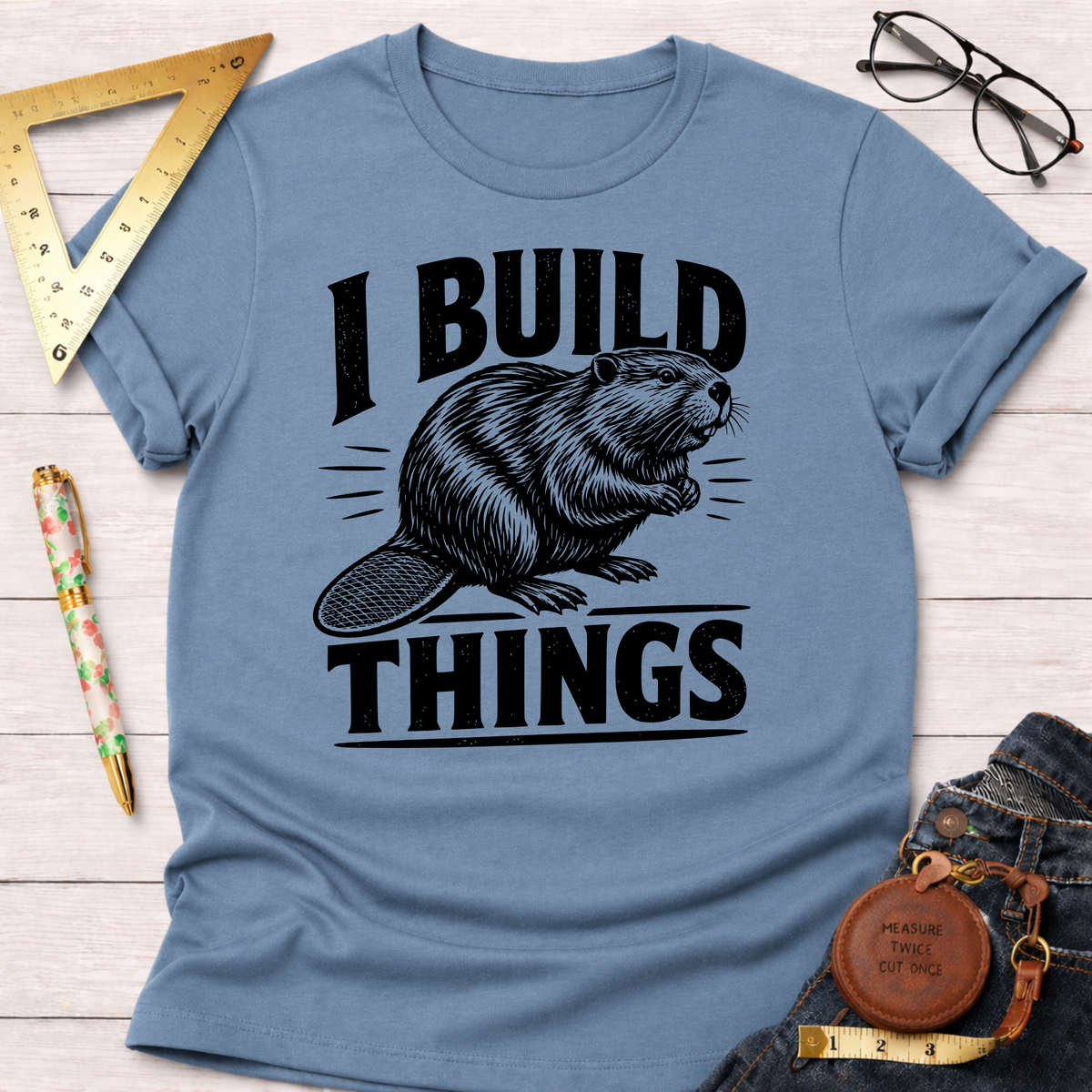 Light blue cotton t-shirt with "I BUILD THINGS" text and a beaver graphic, styled with rolled sleeves.