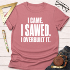 Mauve t-shirt with "I CAME. I SAWED. I OVERBUILT IT." in white text, styled with jeans and tools.