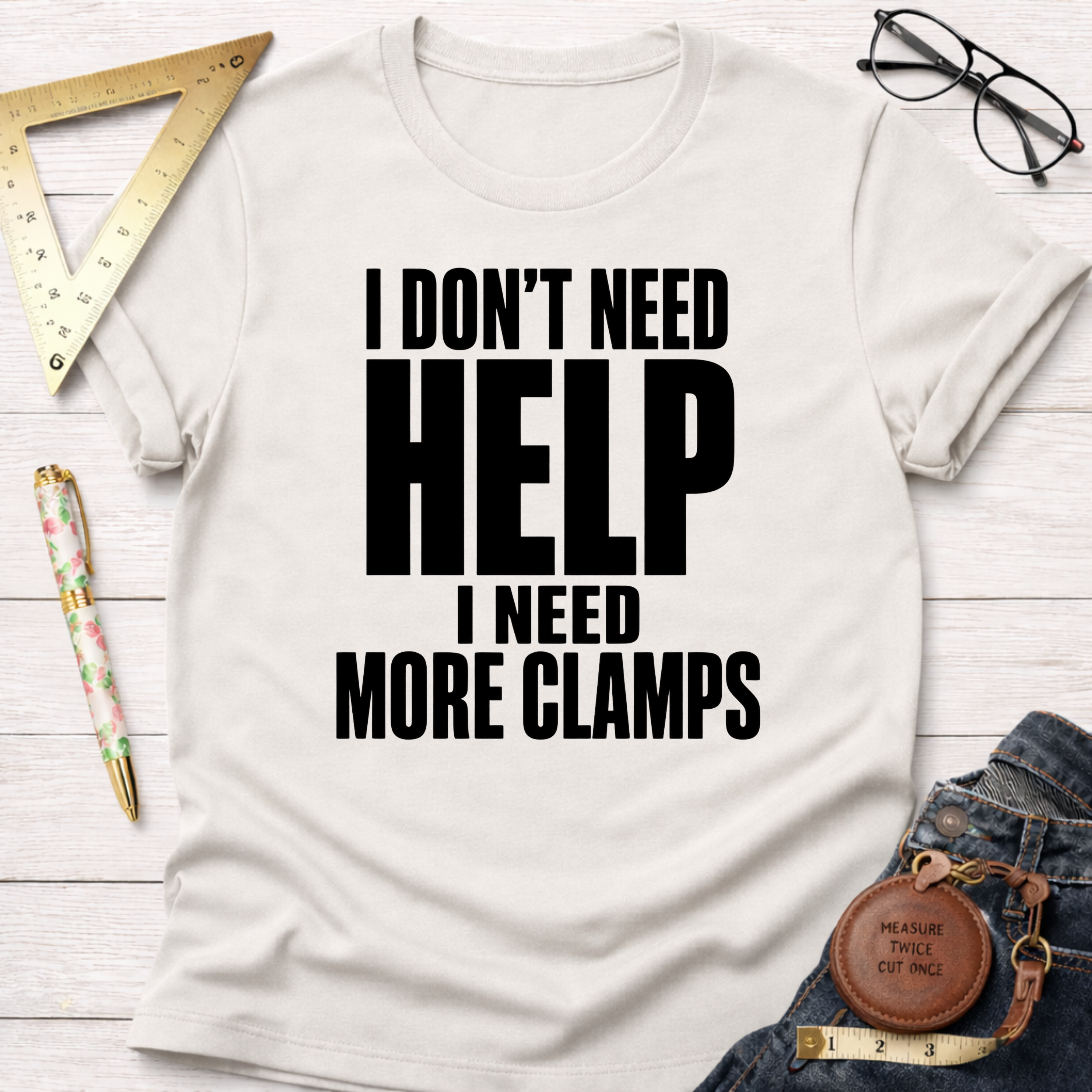 White cotton unisex t-shirt with "I DON'T NEED HELP. I NEED MORE CLAMPS." in black text.