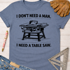 Women's funny woodworking graphic tee shirt for female woodworkers, makers, and DIY builders — Sawdust & Ponytails. Blue cotton tee with "I DON'T NEED A MAN. I NEED A TABLE SAW." graphic.