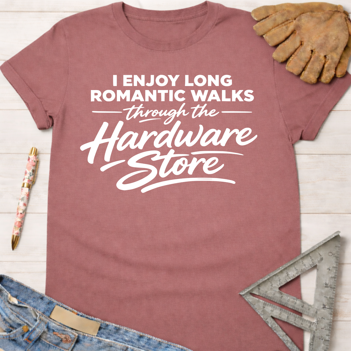 Women's funny woodworking graphic tee shirt for female woodworkers, makers, and DIY builders — Sawdust & Ponytails. Mauve cotton tee with "I Enjoy Long Romantic Walks Through The Hardware Store" in white text.
