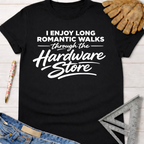 Women's funny woodworking graphic tee shirt for female woodworkers, makers, and DIY builders — Sawdust & Ponytails. Black cotton crewneck t-shirt with "I Enjoy Long Romantic Walks Through The Hardware Store" in white text.