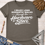 Women's funny woodworking graphic tee shirt for female woodworkers, makers, and DIY builders — Sawdust & Ponytails. Dark gray cotton tee with "I Enjoy Long Romantic Walks Through the Hardware Store" in white text, styled with jeans, pen, glove, and ruler.