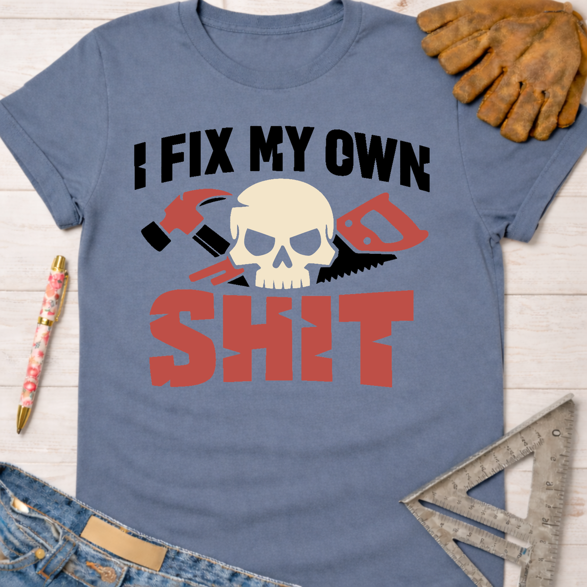 Women's funny woodworking graphic tee shirt for female woodworkers, makers, and DIY builders — Sawdust & Ponytails. Blue t-shirt with "I FIX MY OWN SHIT" text, skull, hammer, and saw graphic.