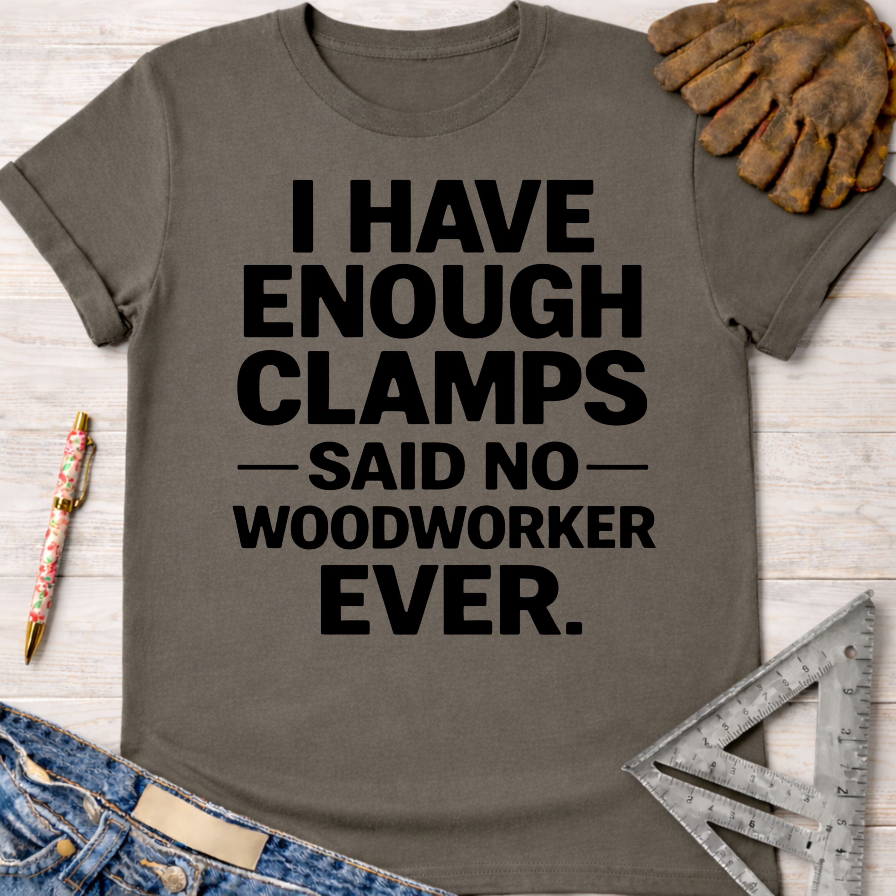 Women's funny woodworking graphic tee shirt for female woodworkers, makers, and DIY builders — Sawdust & Ponytails. Dark gray cotton tee with "I HAVE ENOUGH CLAMPS — SAID NO — WOODWORKER EVER." in black text.