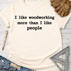 Women's funny woodworking graphic tee shirt for female woodworkers, makers, and DIY builders — Sawdust & Ponytails. Cream t-shirt with "I like woodworking more than I like people" text.