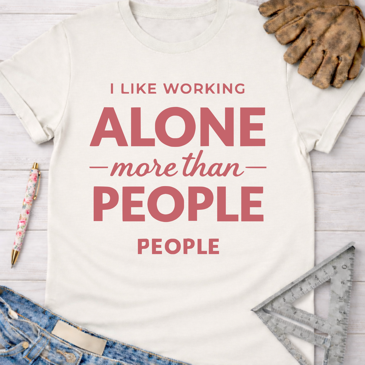 Women's funny woodworking graphic tee shirt for female woodworkers, makers, and DIY builders — Sawdust & Ponytails. Cream cotton tee with "I LIKE WORKING ALONE more than PEOPLE" in red text.