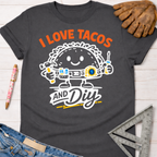 Women's funny woodworking graphic tee shirt for female woodworkers, makers, and DIY builders — Sawdust & Ponytails. Dark gray cotton tee with "I Love Tacos and DIY" graphic featuring a taco character holding tools.