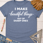 Women's funny woodworking graphic tee shirt for female woodworkers, makers, and DIY builders — Sawdust & Ponytails. Blue cotton tee with "I Make Beautiful Things Out Of Sharp Ones" in white script.