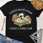 Black cotton Women's funny woodworking graphic tee shirt with "I don't need a man, I need a table saw" text and floral table saw design. Sawdust & Ponytails.