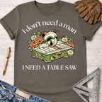 Women's funny woodworking graphic tee shirt for female woodworkers, makers, and DIY builders — Sawdust & Ponytails. Dark gray cotton tee with "I don't need a man, I need a table saw" text and a floral table saw graphic.