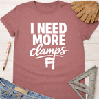 Women's funny woodworking graphic tee shirt for female woodworkers, makers, and DIY builders — Sawdust & Ponytails. Mauve short-sleeve t-shirt with "I NEED MORE clamps" text and clamp graphic.